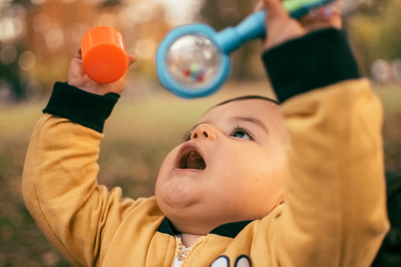 Cute baby playing outdoors with a colorful toy, enjoying the autumn day.